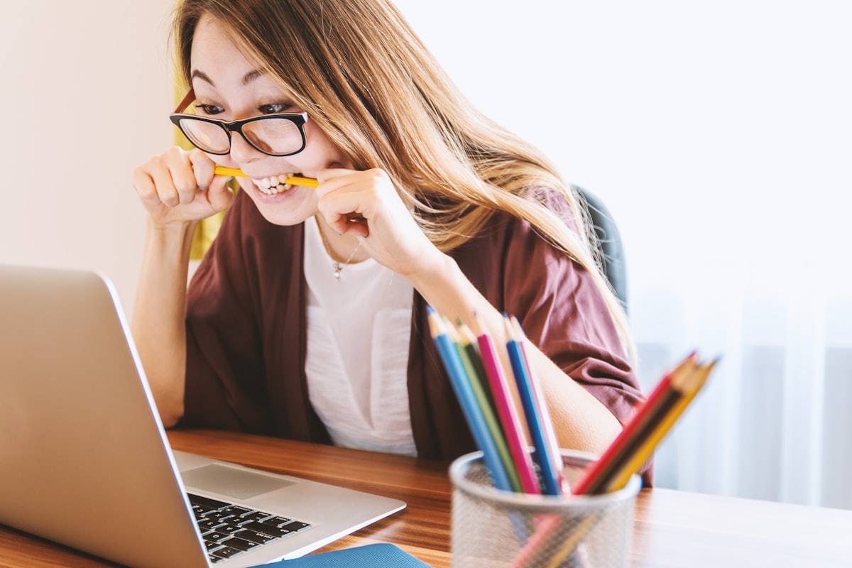 A student looking frustrated while studying with a laptop and notebook
