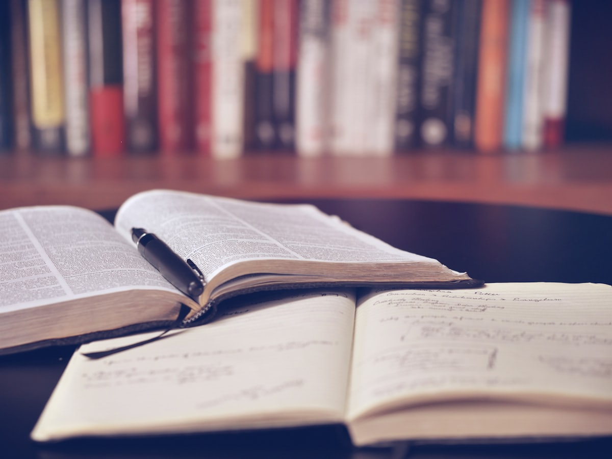 An open book and a handwritten notebook on a desk